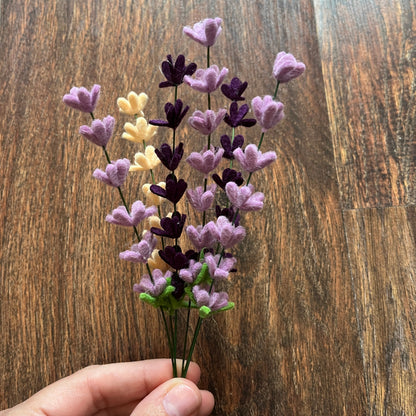 Hand holding a small bouquet of artificial flowers on a wooden surface